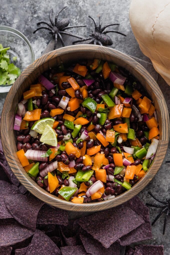 Spooky-themed black bean dip served in a bowl with tortilla chips scattered nearby for a pre-trick-or-treat snack.