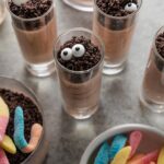 Small batch of Halloween dirt cup shooters, with chocolate pudding, crushed Oreos, and candy eyeballs.