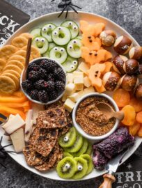 Assemble this cute Halloween-inspired fruit and cheese board with a variety of snacks and a few simple accessories. Share it as an appetizer at the neighborhood party or use it as an easy grazing dinner before the kids scoot off to trick or treat!