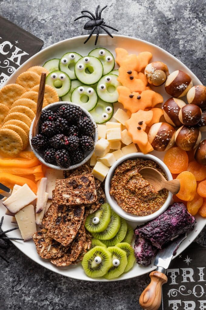 Assemble this cute Halloween-inspired fruit and cheese board with a variety of snacks and a few simple accessories. Share it as an appetizer at the neighborhood party or use it as an easy grazing dinner before the kids scoot off to trick or treat!
