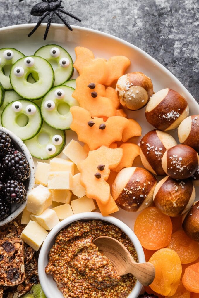 Close up of cantaloupe cut out in a bat shape with mini chocolate chips positioned as "eyes."
