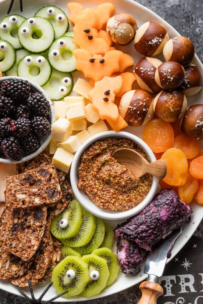 Overhead view of a Halloween-themed fruit, cheese, and veggie board.