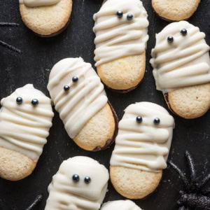 Tray of Milano cookies dipped and decorated with white chocolate to look like cute, spooky Mummies for a Halloween treat.