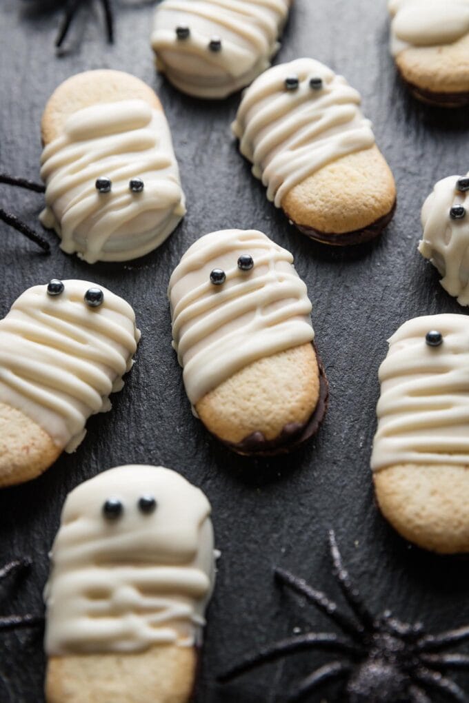 Angled close up of a Milano cookie dipped to look like a mummy and served on a tray at a Halloween party.