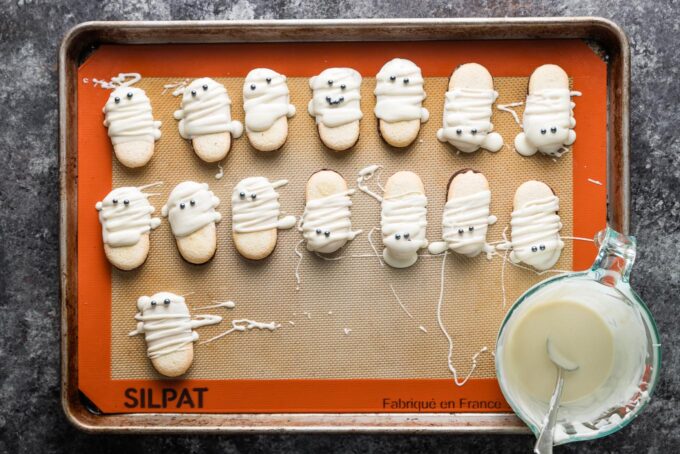 Milano cookies decorated to look like cute mummies, left to set on a large baking sheet.