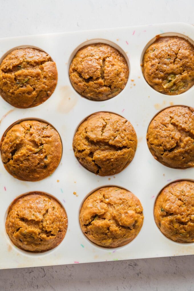 Silicone muffin baking tin filled with pumpkin zucchini muffins fresh out of the oven.