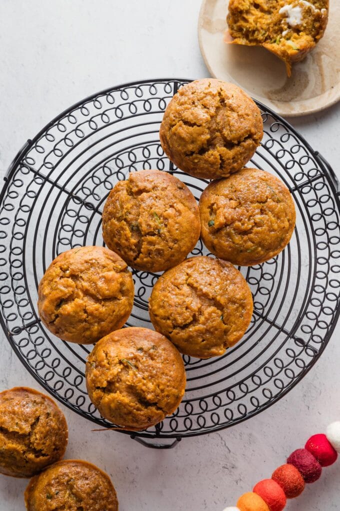 Batch of pumpkin zucchini muffins cooling on a countertop.