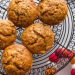Large pumpkin zucchini muffins cooling on a black wire rack.
