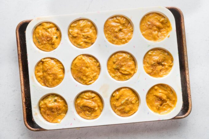 Pumpkin zucchini muffin batter portioned among muffin wells and ready to bake.