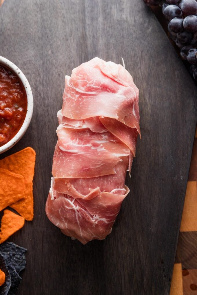 Log of pre-sliced mozzarella cheese wrapped in prosciutto to slightly resemble a spooky arm.