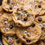 Close up of Halloween-themed chocolate chip cookies piled on a large black plate.