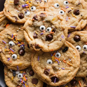 Close up of Halloween-themed chocolate chip cookies piled on a large black plate.