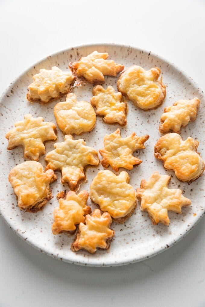 Small plate filled with baked pie crust leaves, acorns, and pumpkins for decorating Thanksgiving pies.
