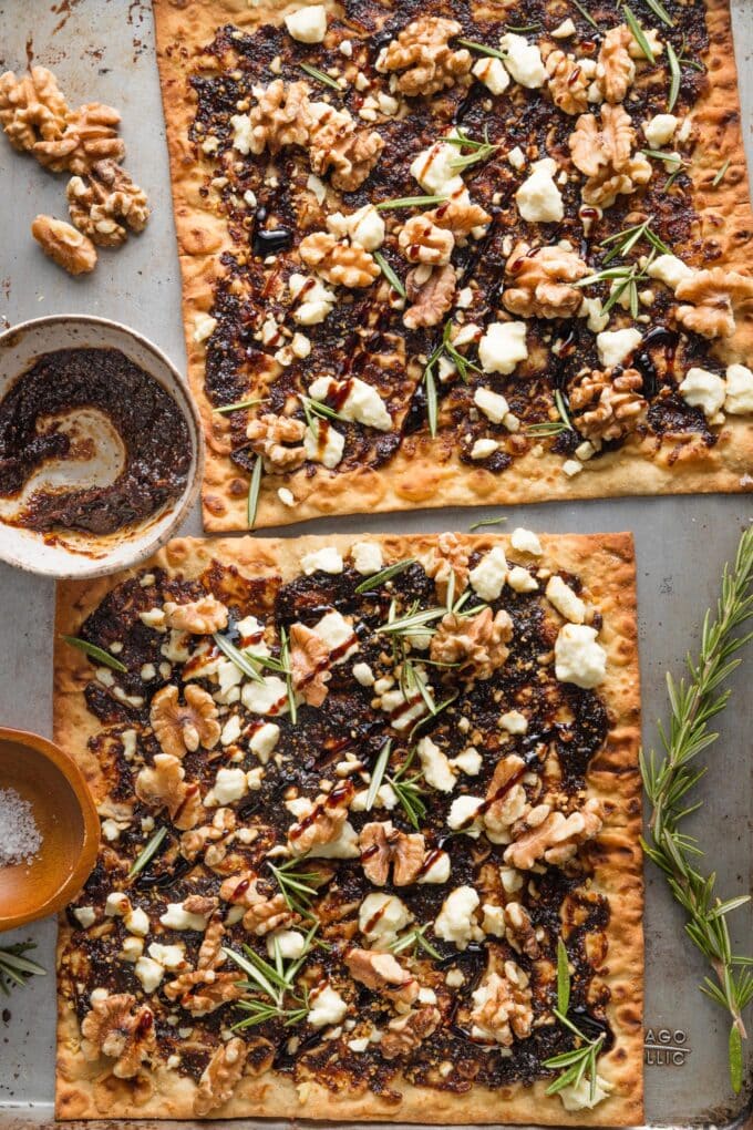 Fig, walnut, and feta flatbreads just baked on a sheet pan and topped with rosemary, sea salt, and balsamic glaze.