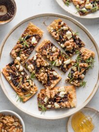 Flatbreads made with fig butter, toasted walnuts, feta, fresh rosemary, sliced and plated on a platter as appetizer bites.