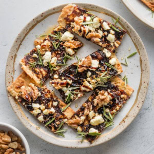 Small plate filled with fig, balsamic, and walnut flatbreads for a little appetizer.
