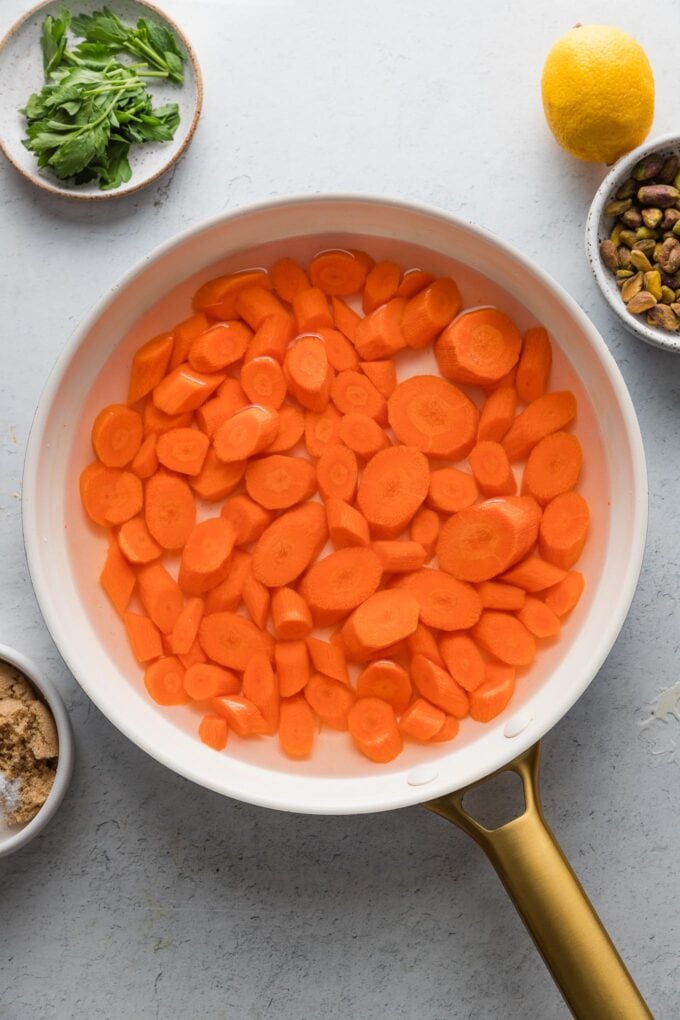 Sliced carrots covered in water in a small skillet.