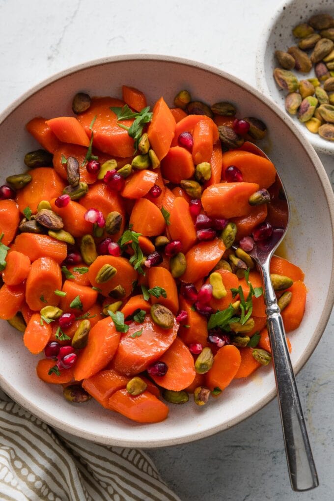 Side dish of glazed carrots with pistachios and pomegranate arils.