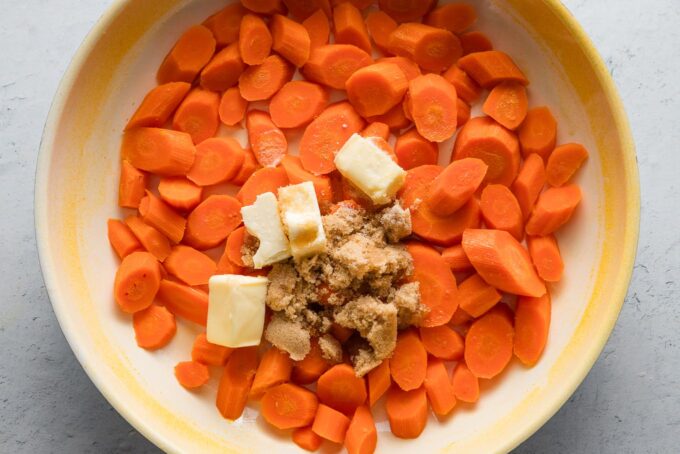 Butter, brown sugar, salt, and lemon juice added to softened carrots in a skillet.