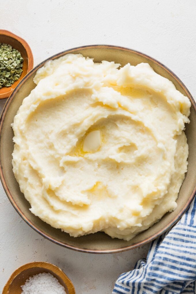 Large bowl of mashed potatoes served with extra butter.