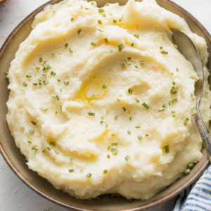 Bowl of creamy mashed potatoes with butter and chives.