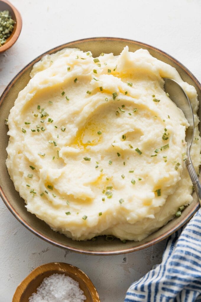 Bowl of creamy mashed potatoes with butter and chives.