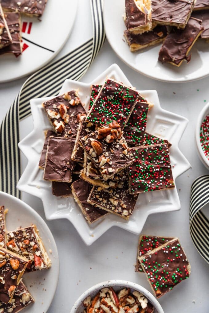 Snowflake-shaped plate full of Christmas cracker candy, some plain, some with pecans, some with sprinkles.