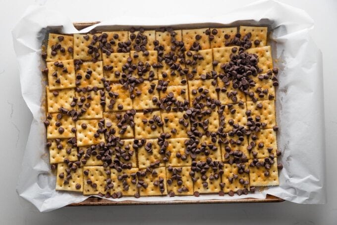 Chocolate chips scattered over caramel and Saltines.