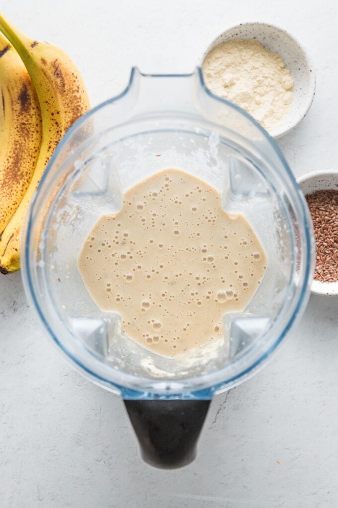 Overhead view of a just-blended banana protein shake inside of the blender.