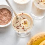 Overhead view of two simple banana protein shakes with almond milk and flaxseeds, in glasses and ready to be enjoyed.
