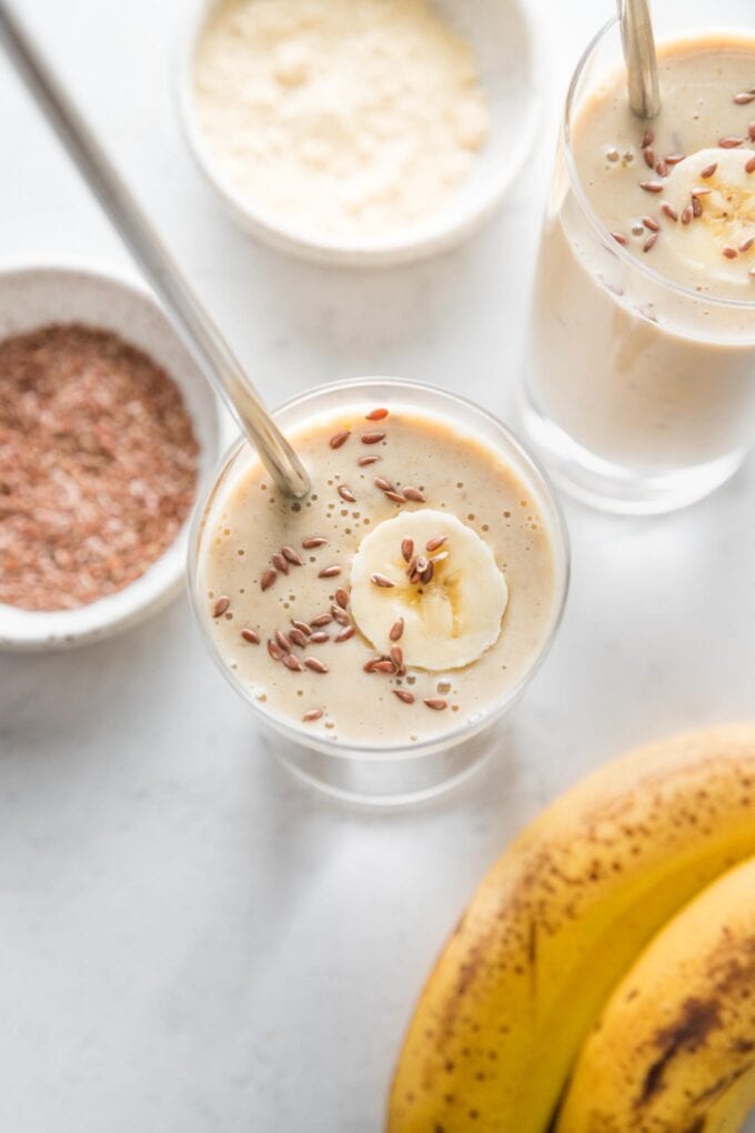 Overhead view of two simple banana protein shakes with almond milk and flaxseeds, in glasses and ready to be enjoyed.