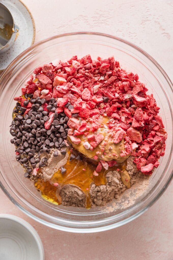 Clear glass bowl filled with the ingredients for chocolate strawberry protein bites, ready to mix together.