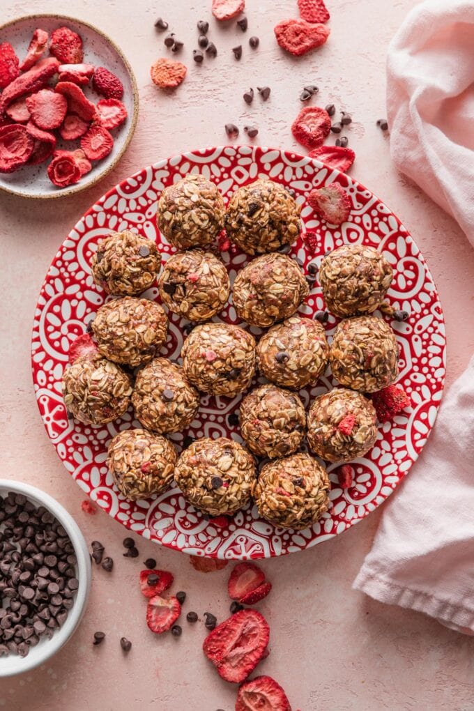 Countertop full of strawberry chocolate protein bites, just rolled and served on a small plate.