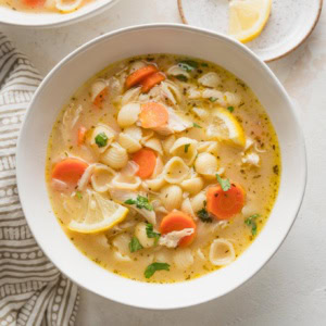 Small bowl full of lemon chicken soup with pasta and veggies.