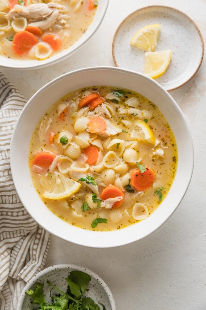 Small bowl full of lemon chicken soup with pasta and veggies.