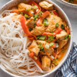 Small ceramic bowl full of a homemade Thai-inspired red chicken curry with rice noodles.