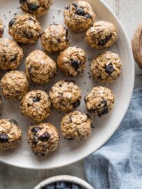 Small plate piled with small blueberry chia energy bites and a blue kitchen towel nearby.