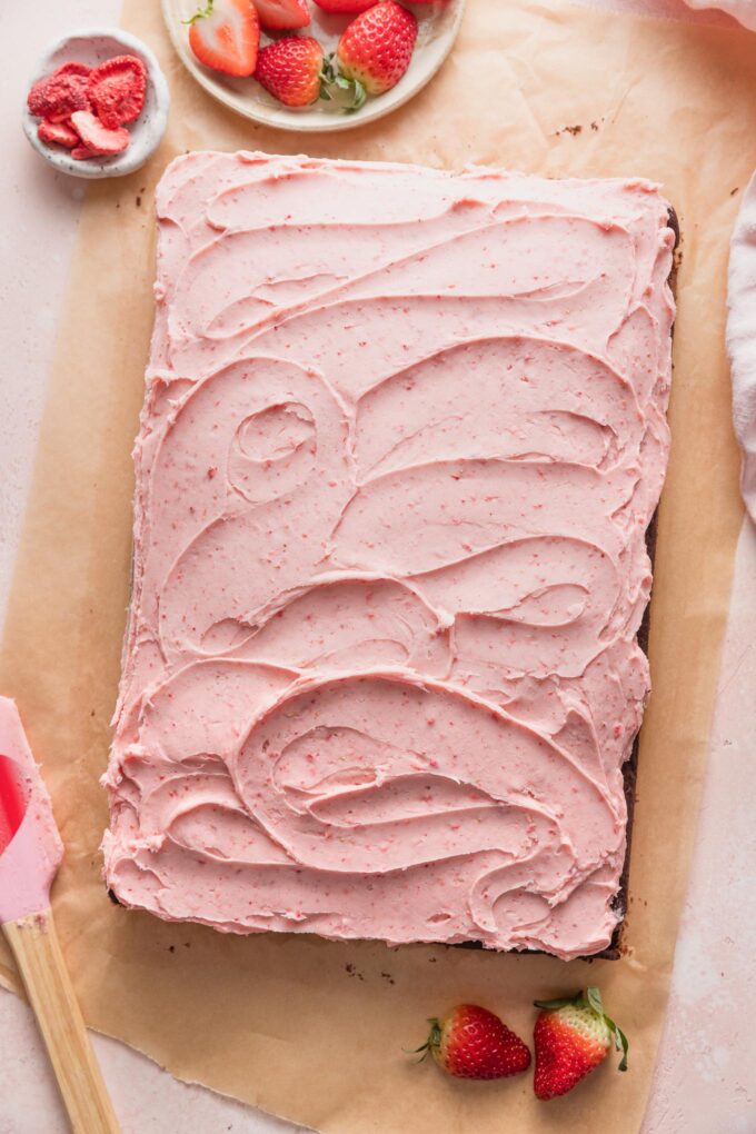 Strawberry frosting swirled on top of a chocolate sheet cake.