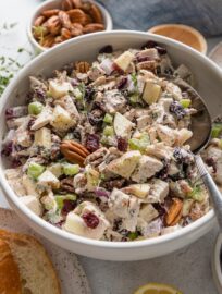 Angled view of a large white bowl full of cranberry pecan chicken salad made with Greek yogurt, fresh thyme, apple, and celery.