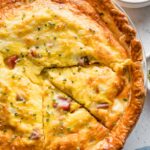 Close up of a ham and Swiss quiche with one slice cut out.