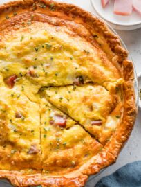 Close up of a ham and Swiss quiche with one slice cut out.