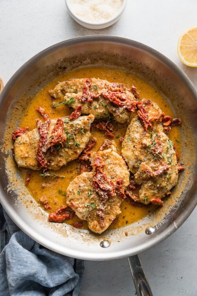 Overhead view of a large aluminum skillet filled with chicken in a creamy sun dried tomato sauce.