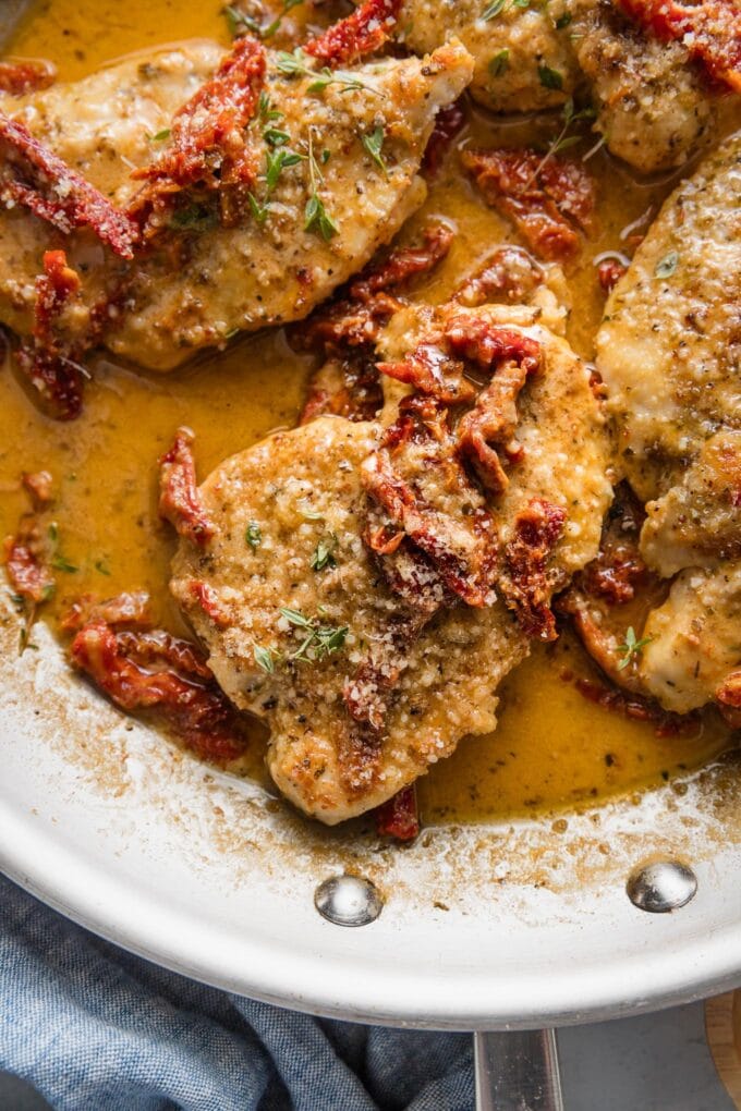 Close up of a chicken breast in creamy sun dried tomato sauce with Parmesan and fresh thyme.
