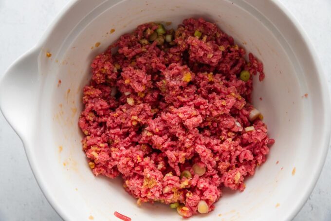Meatball mixture in a large white mixing bowl.