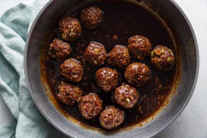 Baked Asian meatballs simmering in a sweet and sticky homemade pan sauce.