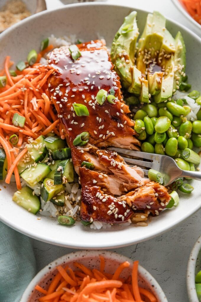Close up of flaky salmon filets baked with a homemade teriyaki sauce, zoomed in to show how a fork can easily break the salmon into pieces.