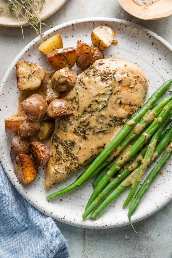 Plated Dijon chicken and potatoes served with green beans and extra drizzled Dijon cream sauce.