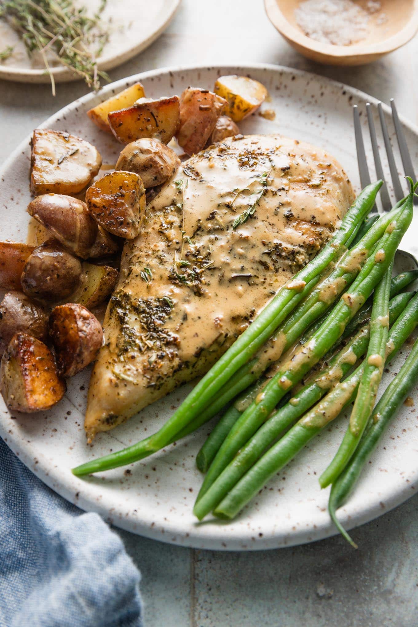 Dinner plate of creamy Dijon chicken, skillet-fried potatoes, and green beans, all dressed with a light Dijon cream sauce.