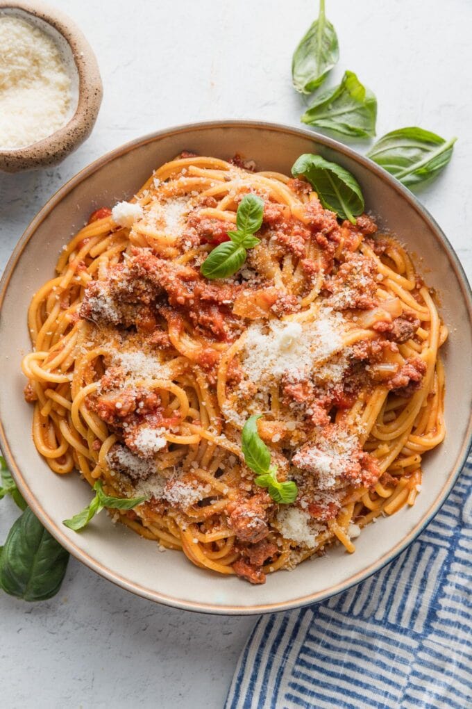 Bowl full of spaghetti with meat sauce made in the Instant Pot pressure cooker and topped with Parmesan and basil.