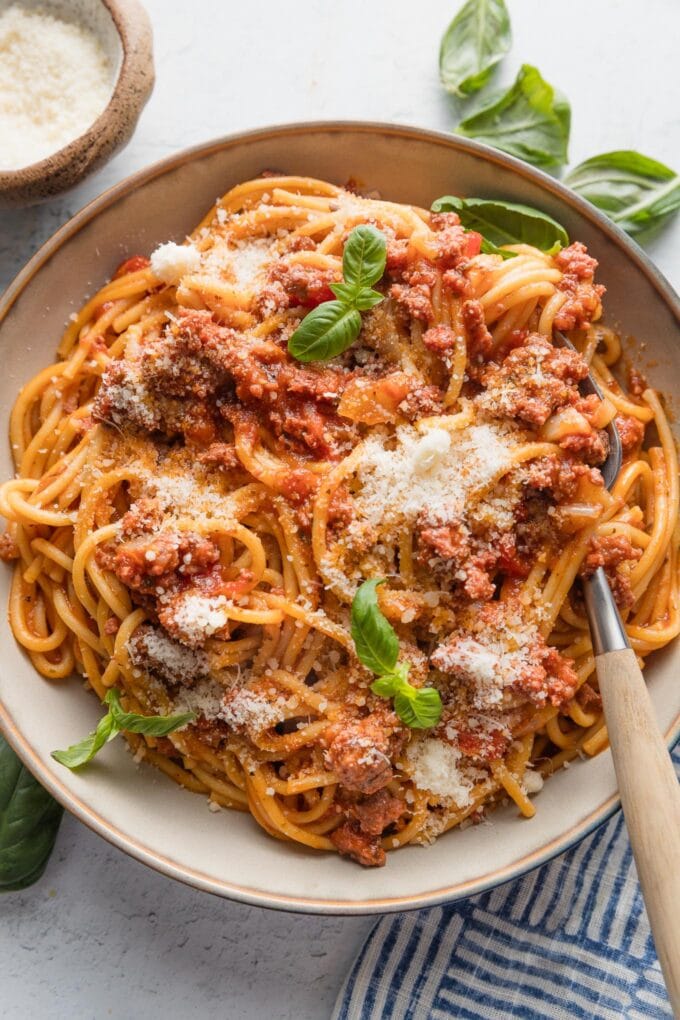Spaghetti with meat sauce made in the Instant Pot, topped with fresh basil and fresh grated Parmesan.